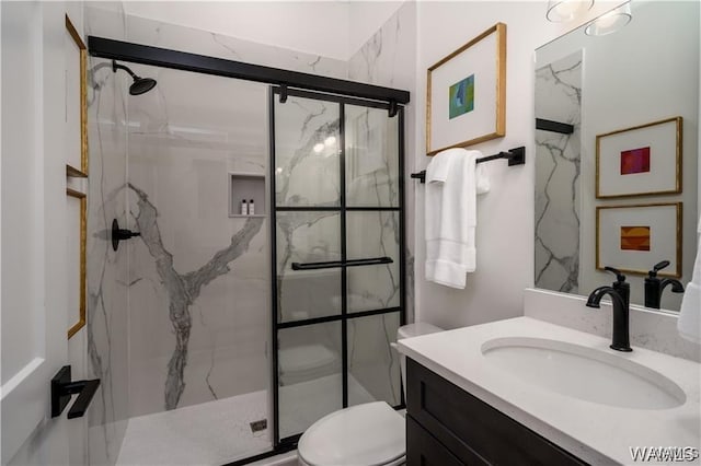 bathroom featuring a shower with shower door, toilet, and vanity