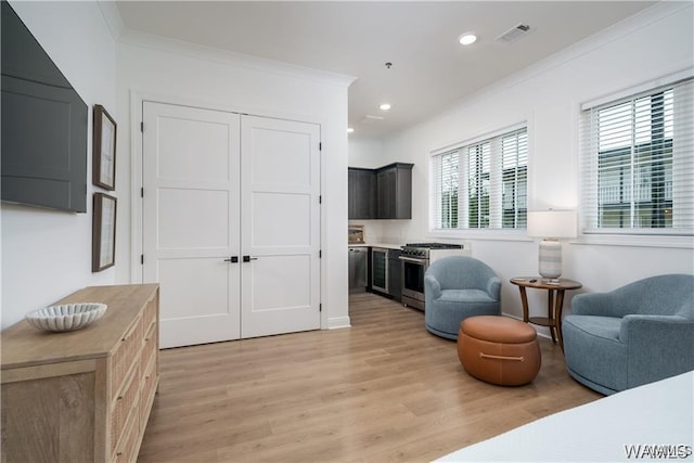 sitting room with crown molding and light hardwood / wood-style floors