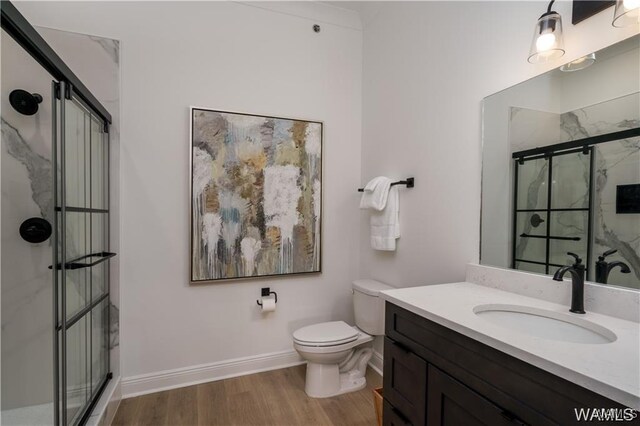 bathroom featuring wood-type flooring, toilet, a shower with door, and vanity