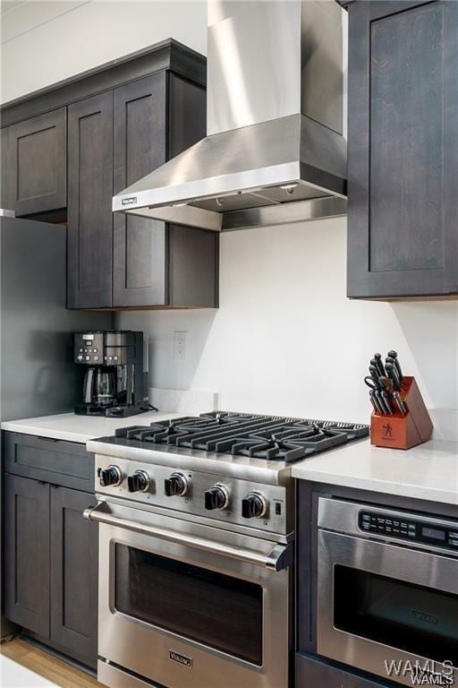 kitchen with light hardwood / wood-style floors, stainless steel range, and wall chimney range hood