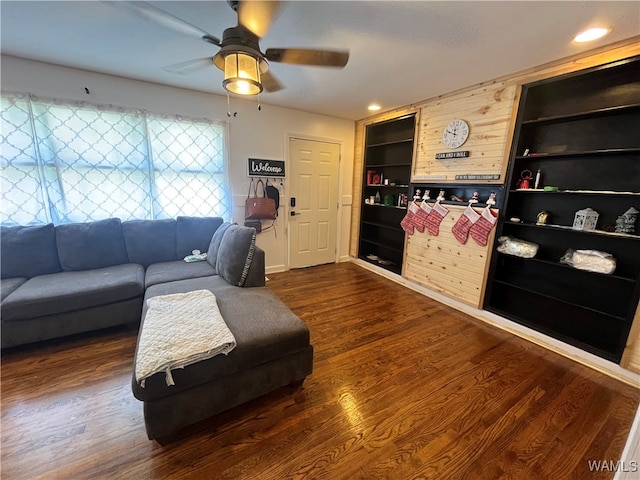 living room featuring built in shelves, dark hardwood / wood-style floors, and ceiling fan