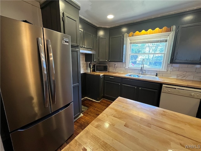 kitchen with butcher block counters, sink, dark hardwood / wood-style flooring, backsplash, and appliances with stainless steel finishes