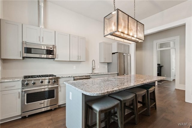 kitchen with dark wood-style flooring, a breakfast bar area, stainless steel appliances, a sink, and a kitchen island