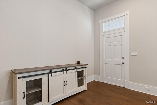 foyer featuring dark wood-type flooring and baseboards