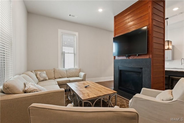 living room with dark wood finished floors, recessed lighting, visible vents, a fireplace with flush hearth, and baseboards