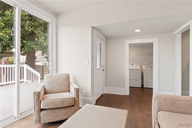 living area featuring washing machine and dryer, baseboards, and wood finished floors