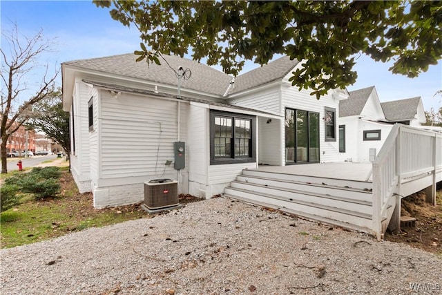 rear view of property featuring central AC, a shingled roof, and a wooden deck