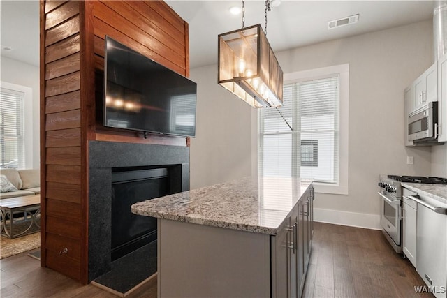 kitchen with appliances with stainless steel finishes, a glass covered fireplace, visible vents, and dark wood finished floors