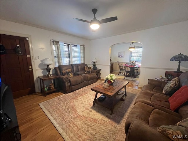 living room with a wealth of natural light, arched walkways, ceiling fan, and wood finished floors