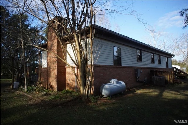 view of side of home featuring brick siding and central air condition unit