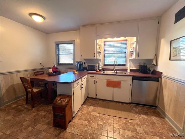 kitchen featuring dishwasher, dark countertops, and white cabinets