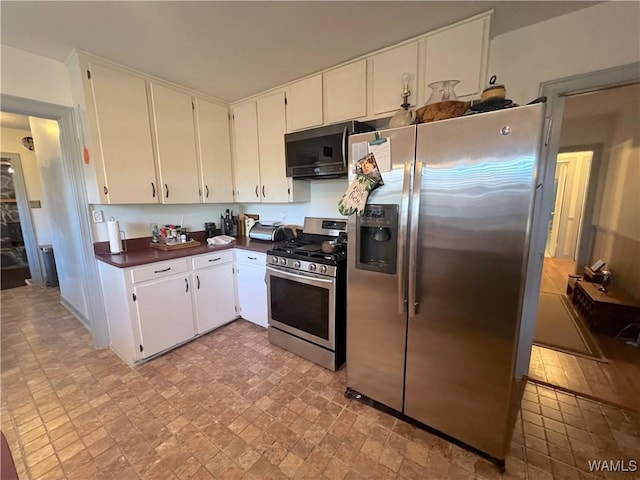 kitchen with stainless steel appliances, dark countertops, and white cabinetry