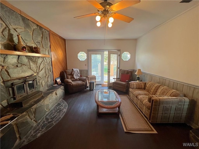 living area with ceiling fan, dark wood-style flooring, wood walls, and wainscoting