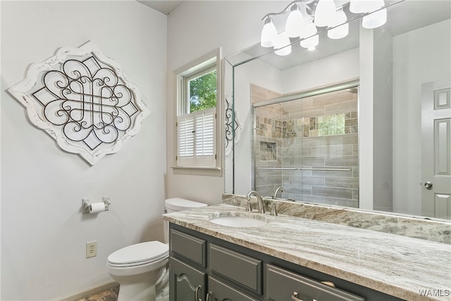 bathroom featuring vanity, toilet, and a shower with shower door