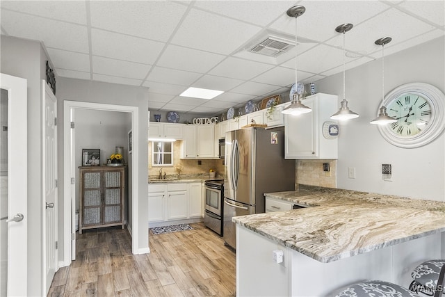 kitchen with stainless steel electric range oven, kitchen peninsula, light hardwood / wood-style floors, decorative light fixtures, and white cabinets