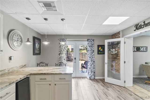 kitchen with white cabinetry, french doors, pendant lighting, light hardwood / wood-style floors, and a paneled ceiling