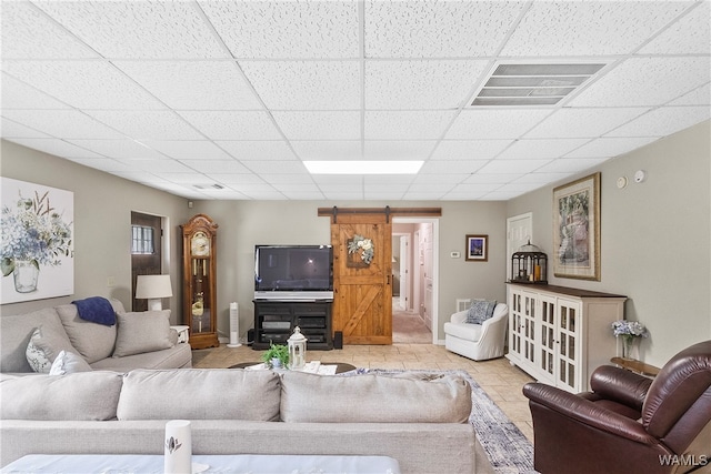 living room with light tile patterned floors, a barn door, and a paneled ceiling