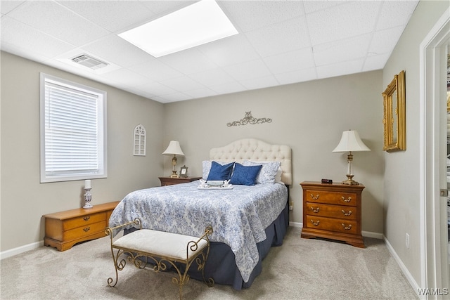 bedroom with light carpet and a drop ceiling