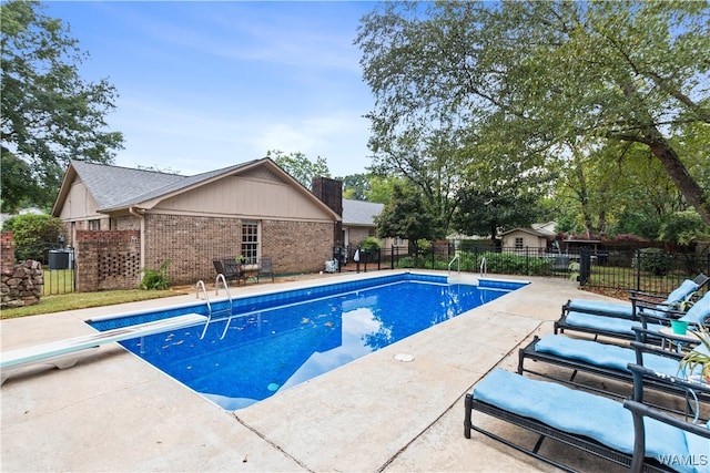 view of swimming pool with a patio and a diving board