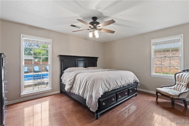 bedroom featuring a textured ceiling, ceiling fan, and dark wood-type flooring