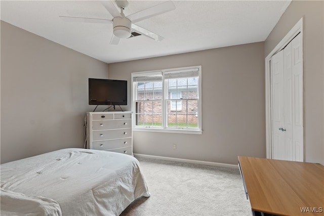 carpeted bedroom with ceiling fan and a closet