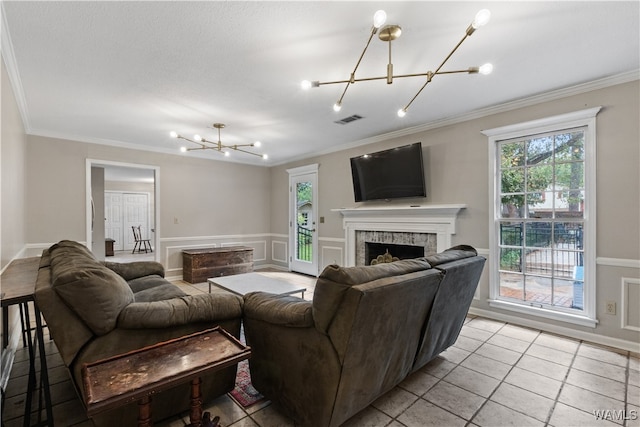 living room with a notable chandelier, light tile patterned flooring, crown molding, and a fireplace