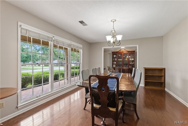 dining room with dark hardwood / wood-style floors, a textured ceiling, and an inviting chandelier