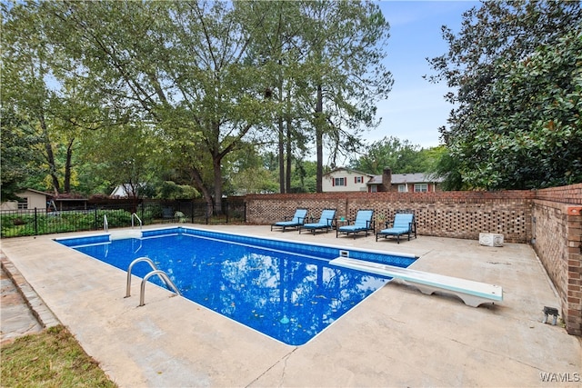 view of pool featuring a diving board and a patio