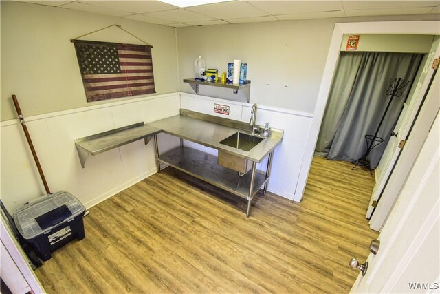 interior space with a paneled ceiling, wood-type flooring, and sink