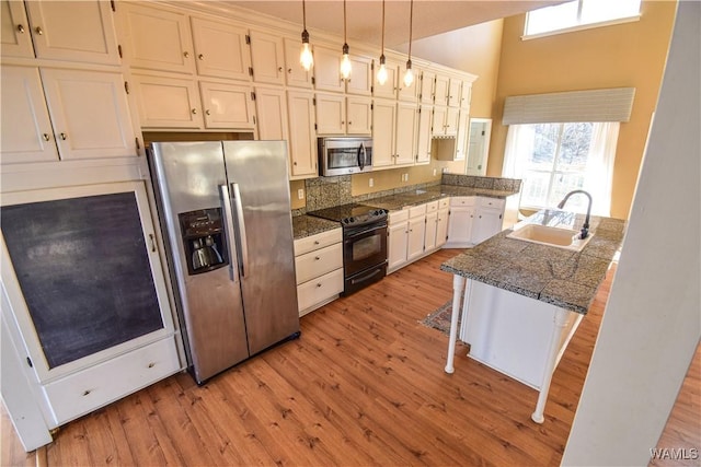 kitchen featuring white cabinetry, appliances with stainless steel finishes, hanging light fixtures, a breakfast bar, and sink