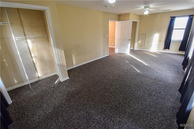 unfurnished bedroom with ceiling fan, a closet, and dark colored carpet