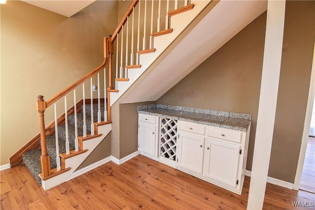 stairs featuring wood-type flooring and bar