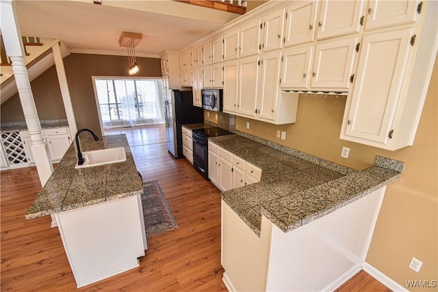 kitchen featuring kitchen peninsula, black electric range, hanging light fixtures, light hardwood / wood-style flooring, and sink