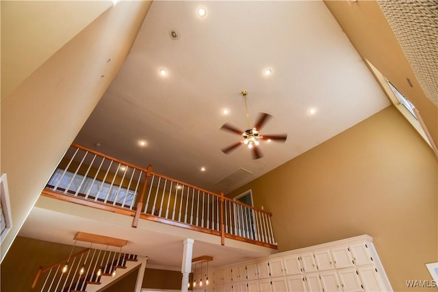 stairs with ceiling fan and high vaulted ceiling