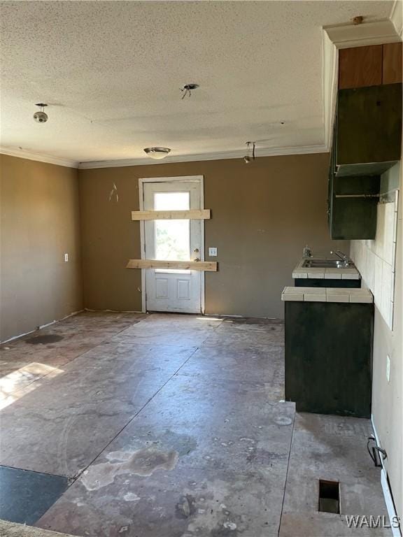 kitchen featuring crown molding, open shelves, tile counters, unfinished concrete flooring, and a textured ceiling