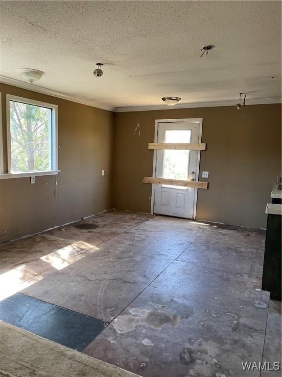spare room with concrete floors, a textured ceiling, and crown molding