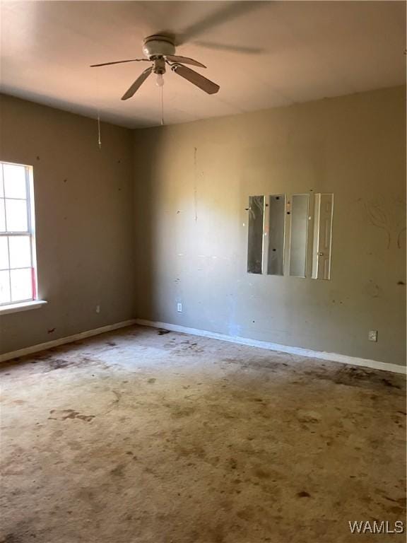 empty room with baseboards, carpet floors, electric panel, and a ceiling fan