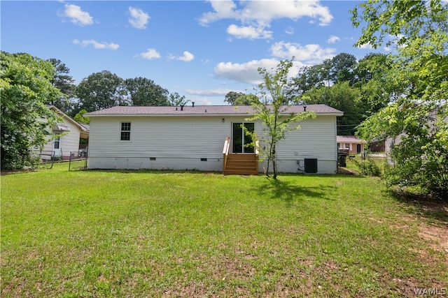 back of property with central AC and a yard