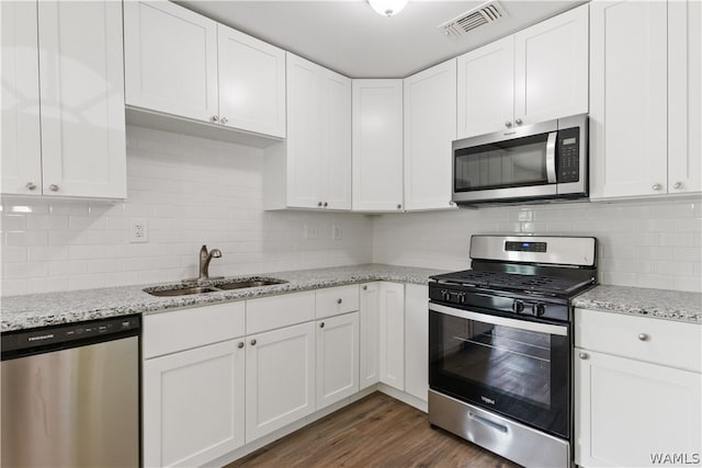 kitchen with white cabinetry, sink, dark wood-type flooring, light stone counters, and appliances with stainless steel finishes