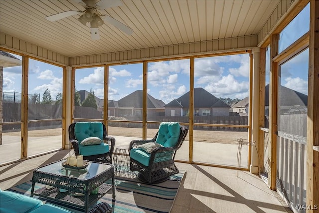 sunroom / solarium featuring ceiling fan and a residential view