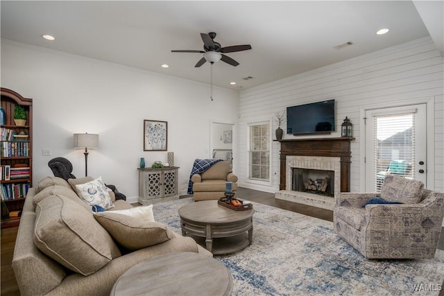 living area with recessed lighting, a fireplace, wood finished floors, visible vents, and crown molding