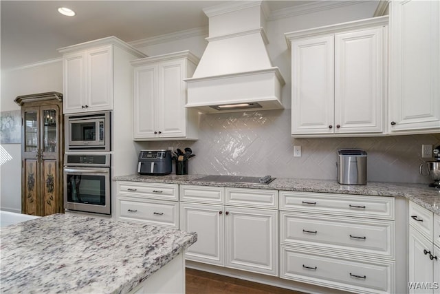 kitchen featuring custom exhaust hood, appliances with stainless steel finishes, white cabinets, and crown molding