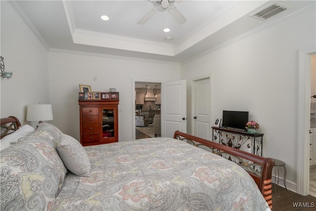 bedroom featuring a ceiling fan, baseboards, visible vents, a tray ceiling, and crown molding