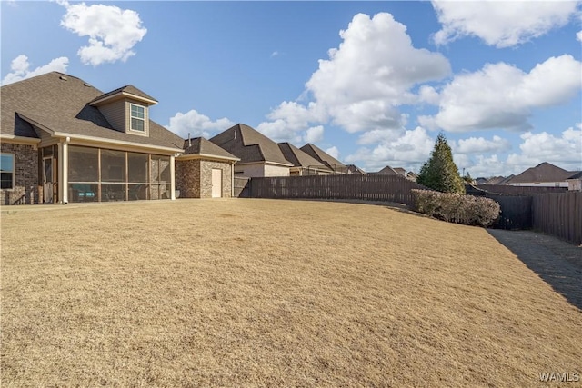 view of yard with a sunroom and a fenced backyard