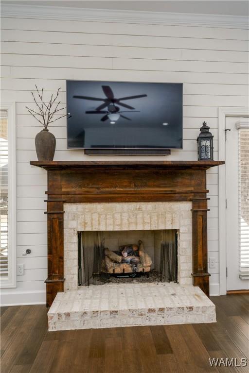 details with ornamental molding, a fireplace, baseboards, and wood finished floors