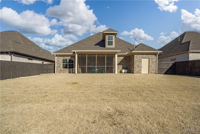 rear view of house featuring a lawn, a fenced backyard, and a sunroom