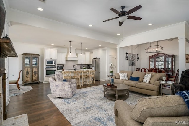 living area featuring ceiling fan with notable chandelier, ornamental molding, dark wood-style flooring, and recessed lighting