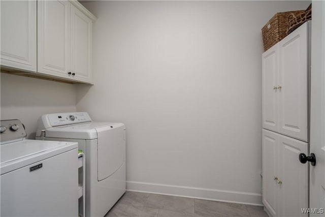 washroom with washing machine and clothes dryer, cabinet space, and baseboards