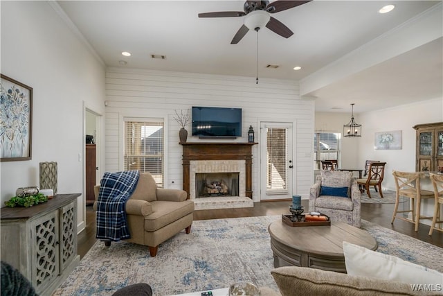 living room featuring ornamental molding, a brick fireplace, wood finished floors, and visible vents