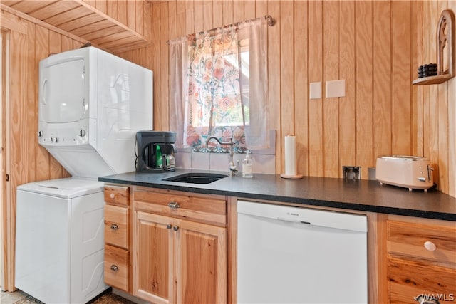 kitchen featuring light brown cabinets, white dishwasher, wooden walls, and sink